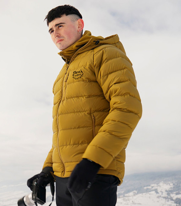 Young man photographer explores snowy field in mountains